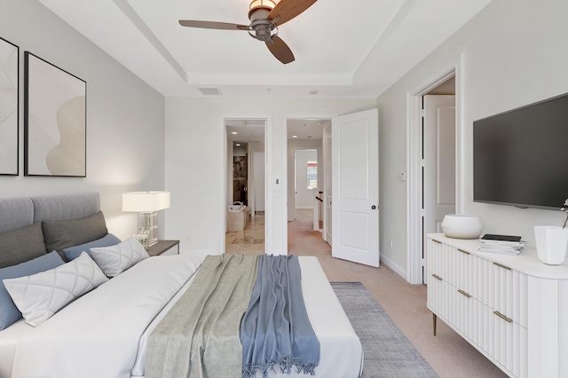 carpeted bedroom with a raised ceiling and ceiling fan