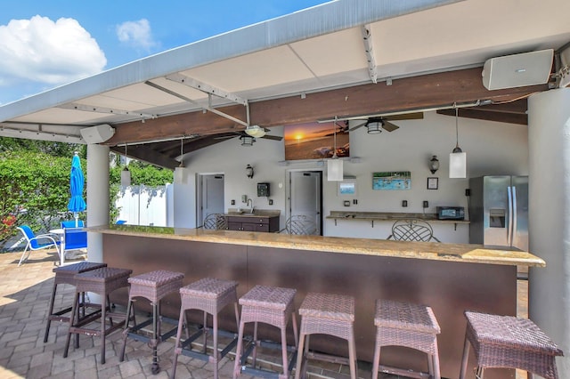 kitchen with a breakfast bar, sink, lofted ceiling, decorative light fixtures, and stainless steel fridge