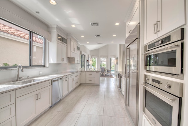 kitchen featuring light stone counters, white cabinets, pendant lighting, sink, and appliances with stainless steel finishes