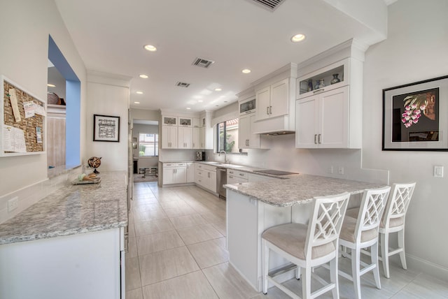 kitchen with stainless steel dishwasher, a kitchen bar, kitchen peninsula, and white cabinetry