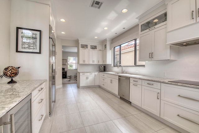 kitchen with white cabinets, light stone counters, plenty of natural light, and stainless steel dishwasher