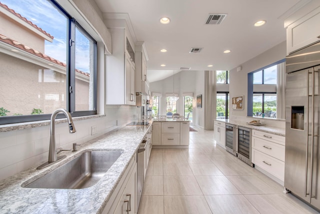 kitchen featuring wine cooler, sink, white cabinetry, stainless steel appliances, and light stone countertops