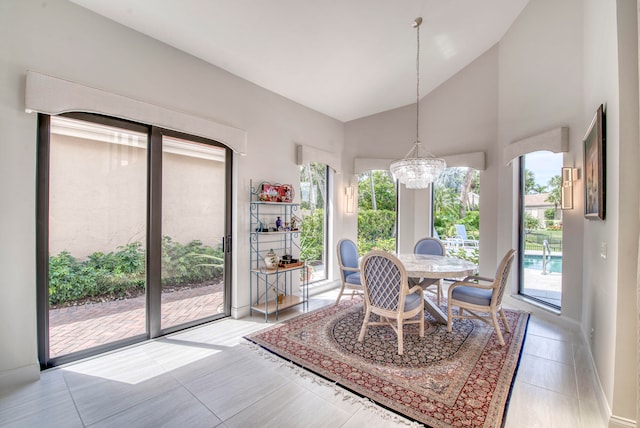 dining space featuring tile patterned flooring, high vaulted ceiling, and a notable chandelier