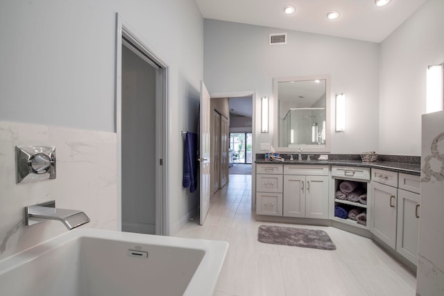 bathroom with independent shower and bath, vanity, vaulted ceiling, and tile patterned floors