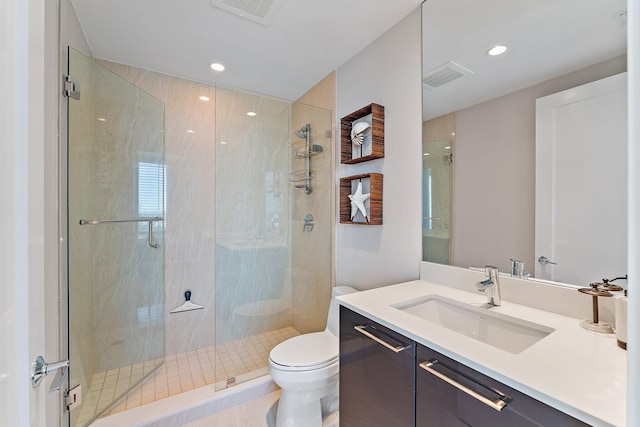 bathroom featuring vanity, toilet, and a shower with shower door