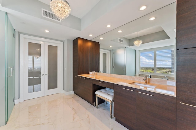 bathroom featuring vanity, a tray ceiling, and a chandelier