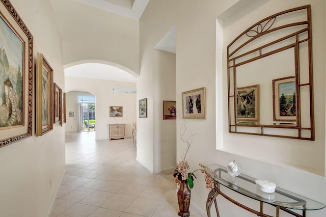 corridor featuring a towering ceiling and light tile patterned floors