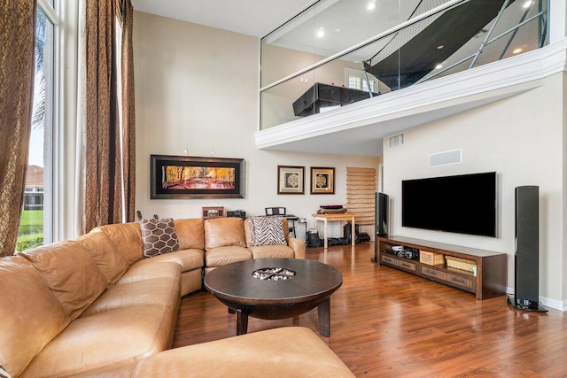 living room with a towering ceiling and hardwood / wood-style flooring