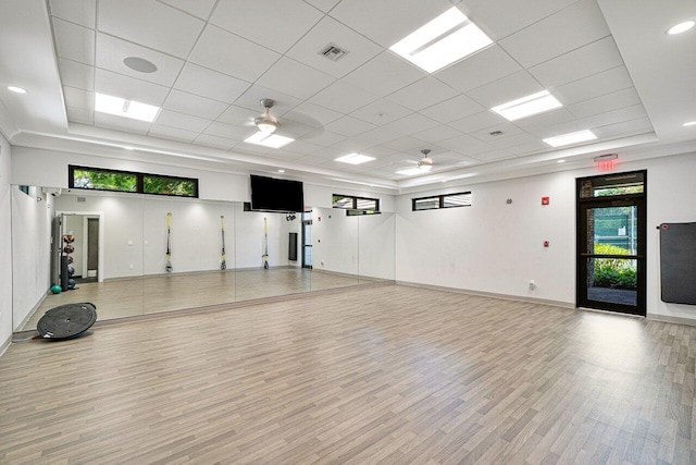 exercise room featuring a paneled ceiling, a tray ceiling, ceiling fan, and light hardwood / wood-style flooring