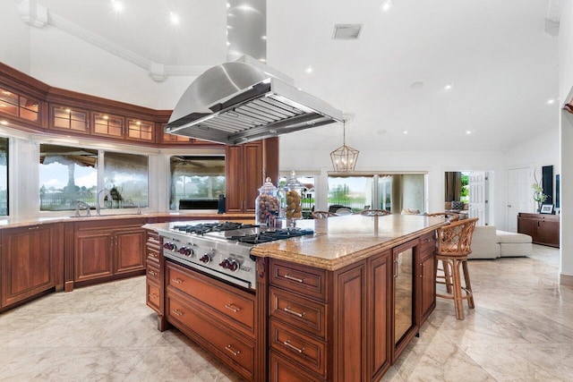 kitchen featuring stainless steel gas cooktop, light stone countertops, island exhaust hood, a center island, and ornamental molding