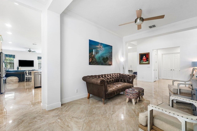 living room featuring ornamental molding, ceiling fan, and a textured ceiling