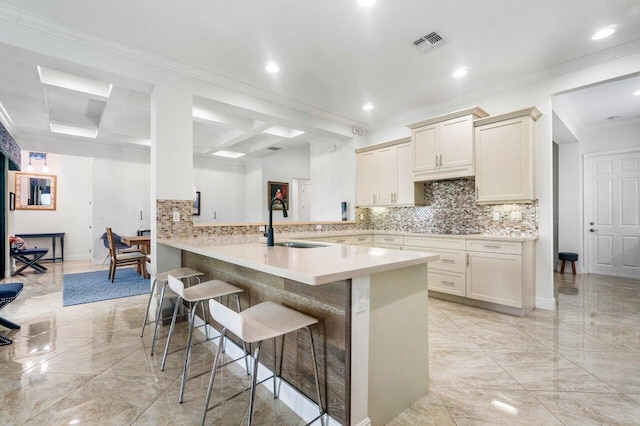 kitchen featuring a breakfast bar, sink, kitchen peninsula, backsplash, and ornamental molding