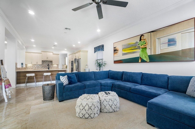 tiled living room featuring a textured ceiling, ornamental molding, sink, and ceiling fan