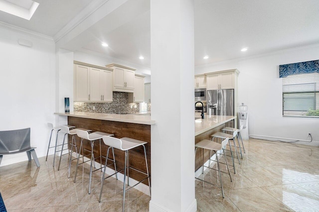 kitchen with tasteful backsplash, kitchen peninsula, a breakfast bar area, stainless steel appliances, and ornamental molding