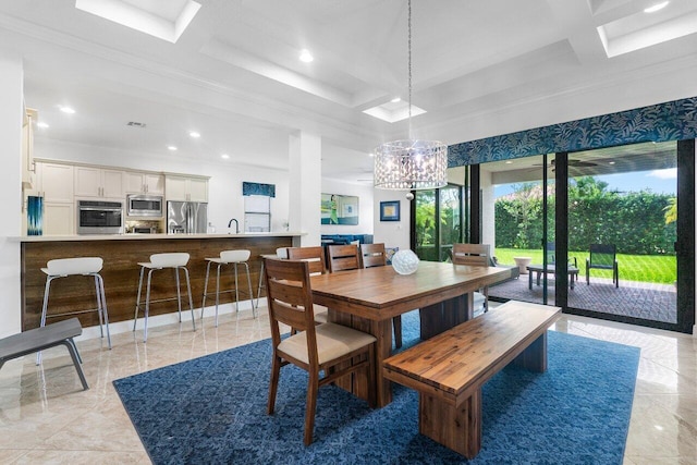 dining room featuring coffered ceiling, crown molding, an inviting chandelier, a skylight, and sink