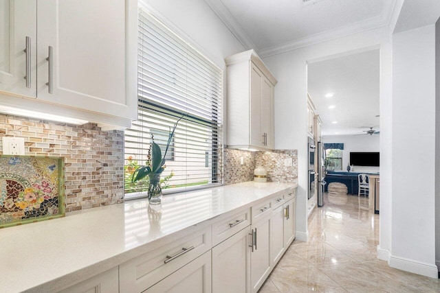 kitchen featuring white cabinets, backsplash, ceiling fan, and crown molding