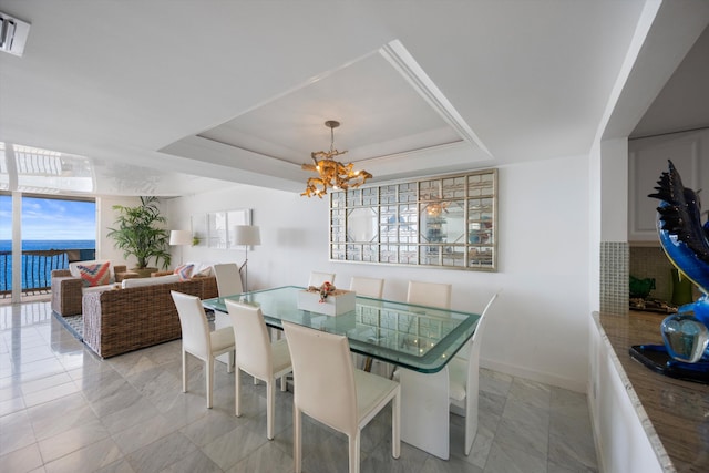 dining room featuring a raised ceiling and a notable chandelier