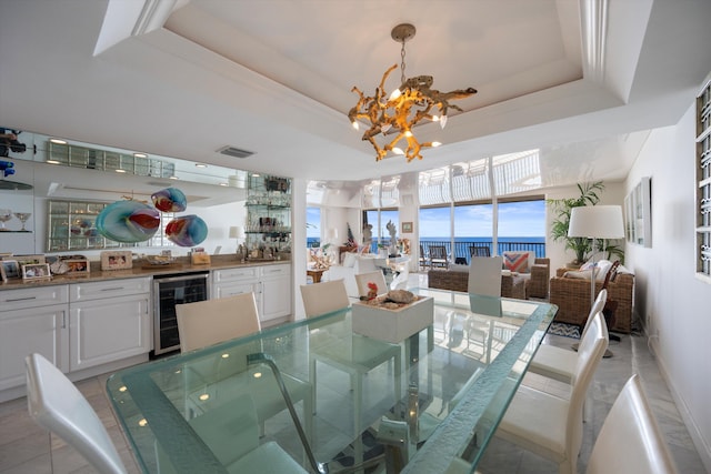 dining space with a tray ceiling, a chandelier, and wine cooler