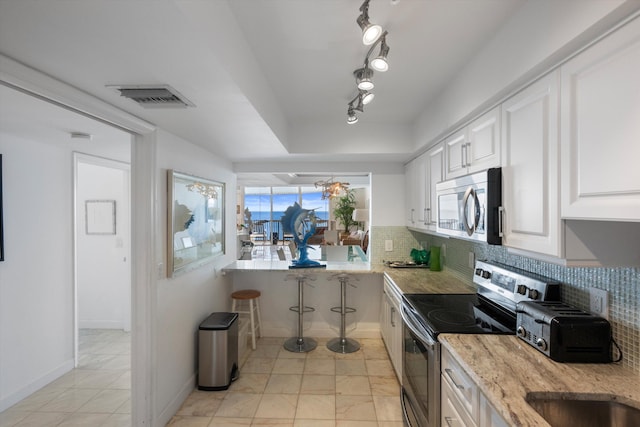 kitchen with appliances with stainless steel finishes, decorative backsplash, a healthy amount of sunlight, and white cabinets