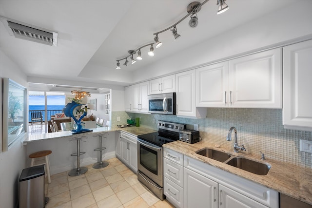 kitchen with light stone counters, sink, white cabinets, decorative backsplash, and appliances with stainless steel finishes