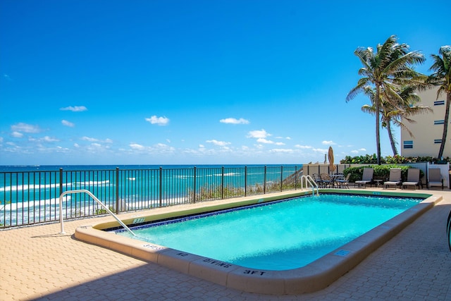 view of swimming pool with a patio and a water view