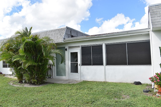 rear view of house with a sunroom and a lawn