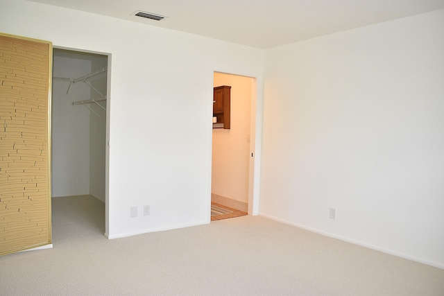 unfurnished bedroom featuring carpet flooring, a spacious closet, and a closet