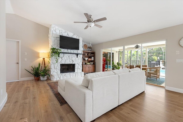 living room featuring ceiling fan, lofted ceiling, a fireplace, and light hardwood / wood-style floors