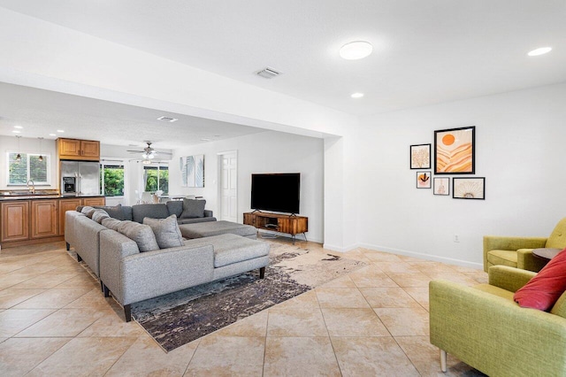 living room featuring ceiling fan, sink, and light tile patterned floors