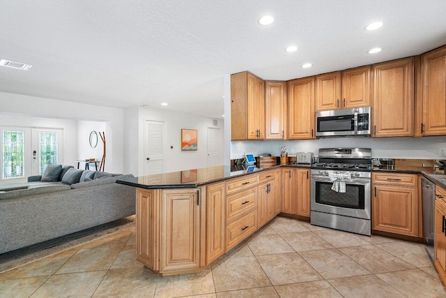 kitchen featuring stainless steel appliances, dark stone countertops, light tile patterned flooring, kitchen peninsula, and a textured ceiling