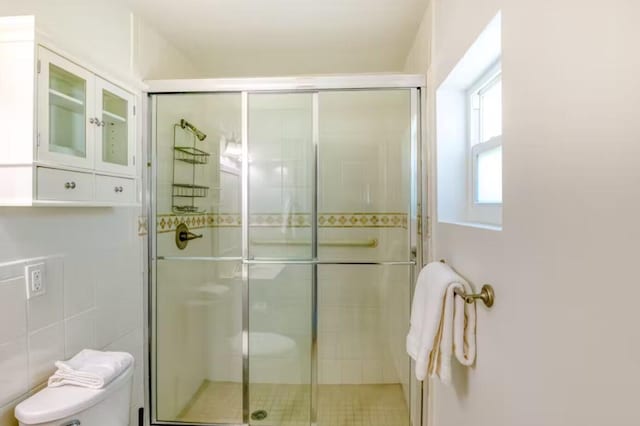 bathroom featuring a shower with shower door and toilet