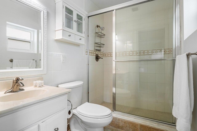 bathroom with vanity, tile walls, toilet, and a shower with door