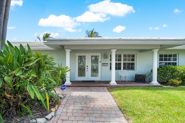 view of exterior entry with french doors, a porch, and a yard