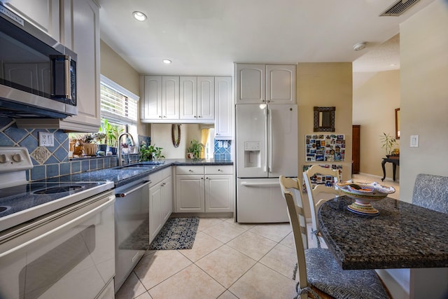 kitchen with light tile patterned flooring, appliances with stainless steel finishes, tasteful backsplash, and sink