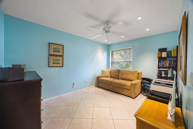 living room with ceiling fan, light tile patterned floors, and a textured ceiling