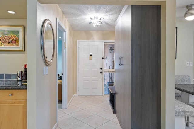 foyer with a textured ceiling and light tile patterned floors