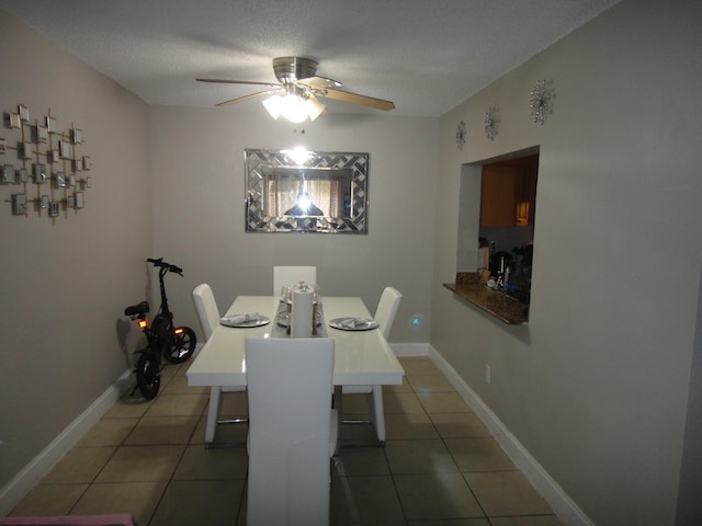 tiled dining space with a textured ceiling and ceiling fan