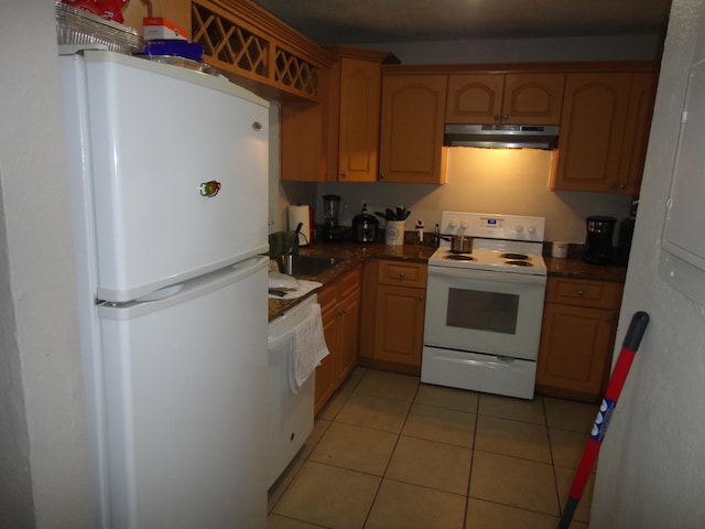 kitchen featuring white appliances, light tile patterned floors, and sink