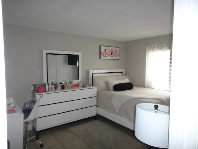 tiled bedroom with a closet and a textured ceiling