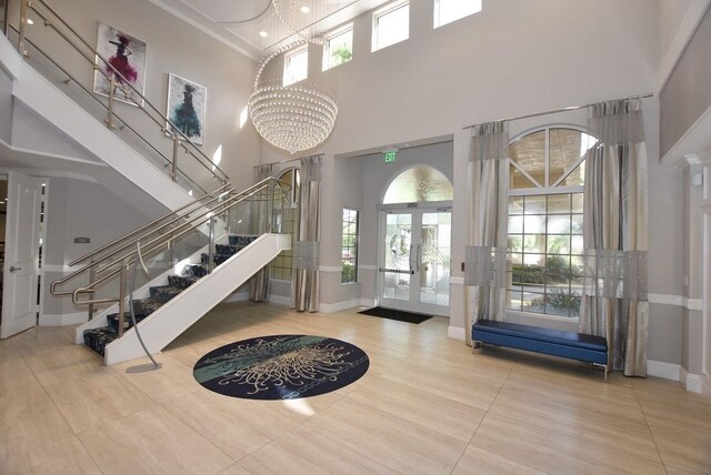 tiled entrance foyer featuring french doors, a towering ceiling, and a notable chandelier