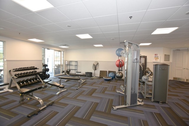 gym with a drop ceiling and dark colored carpet