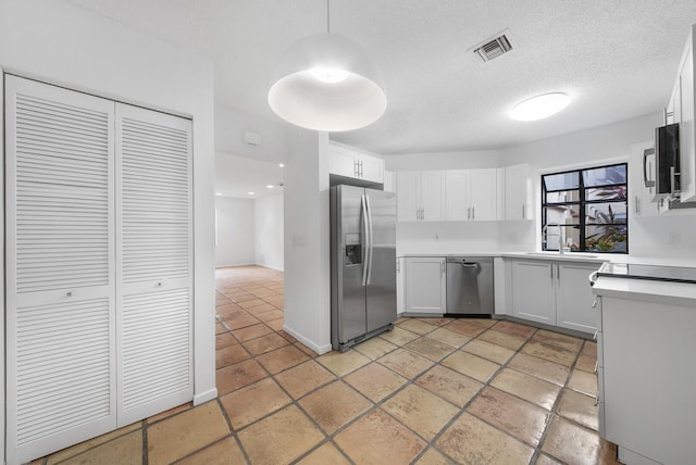 kitchen featuring appliances with stainless steel finishes, a textured ceiling, white cabinetry, and sink