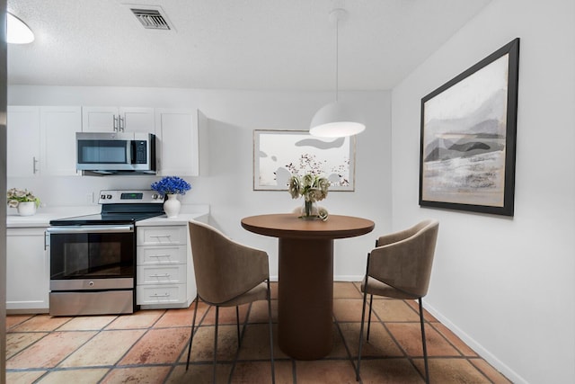 kitchen with white cabinets, hanging light fixtures, and appliances with stainless steel finishes