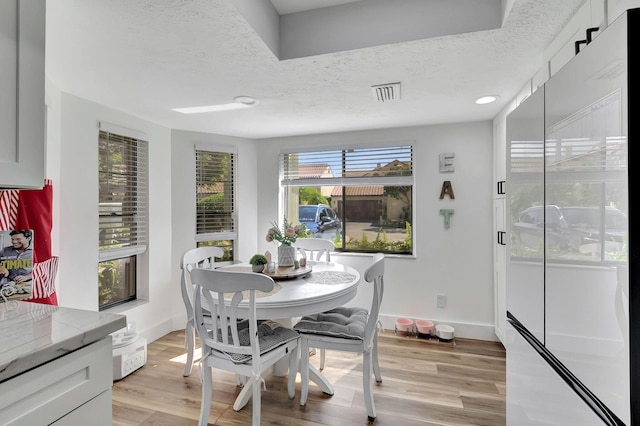 dining space with a textured ceiling and light hardwood / wood-style floors