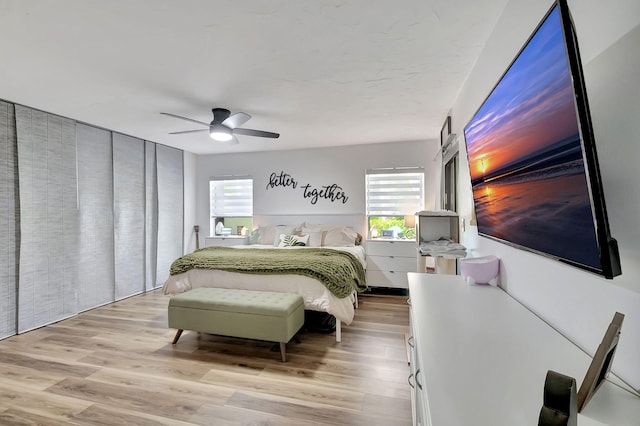 bedroom featuring ceiling fan, light hardwood / wood-style flooring, and multiple windows