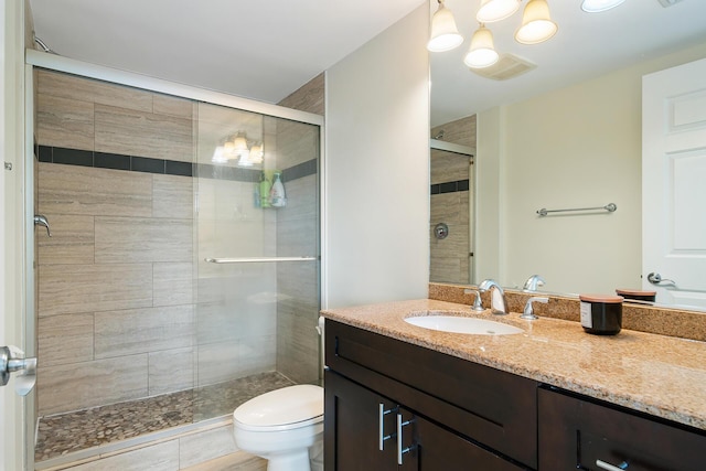 bathroom with vanity, a shower with door, and toilet