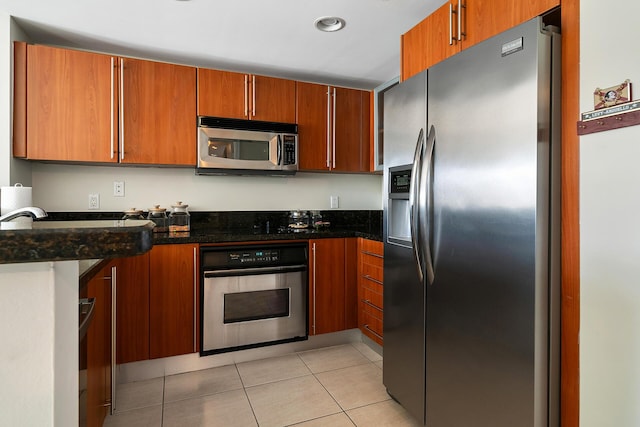 kitchen with light tile patterned floors, dark stone counters, and appliances with stainless steel finishes