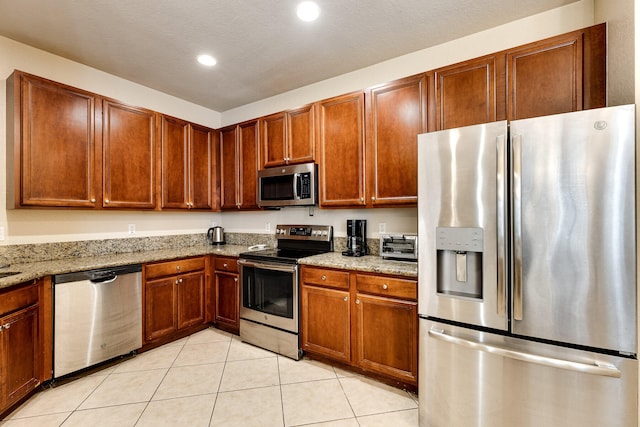 kitchen featuring light stone countertops, a textured ceiling, appliances with stainless steel finishes, and light tile patterned floors