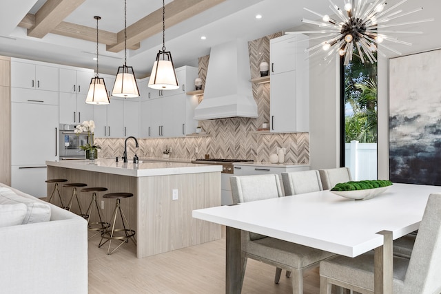 kitchen featuring high quality appliances, custom range hood, hanging light fixtures, and a kitchen bar