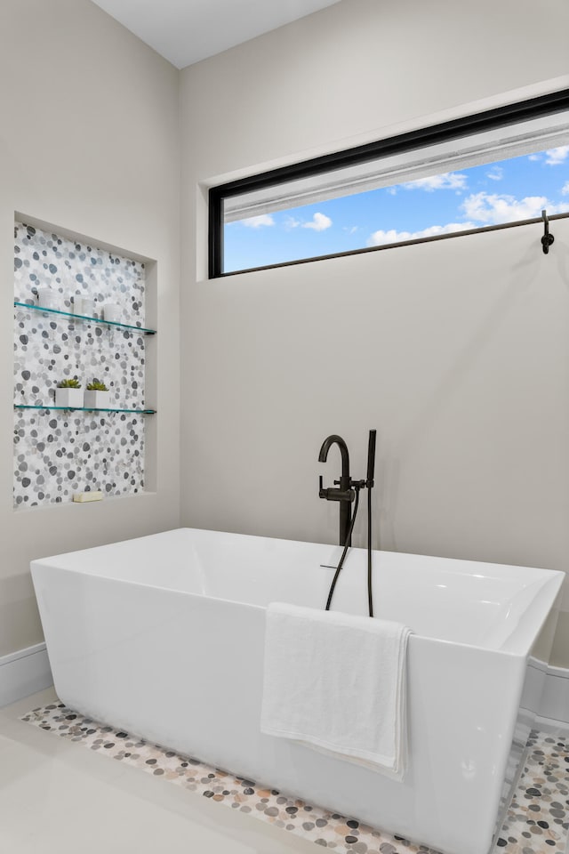 bathroom with tile patterned floors and a tub to relax in